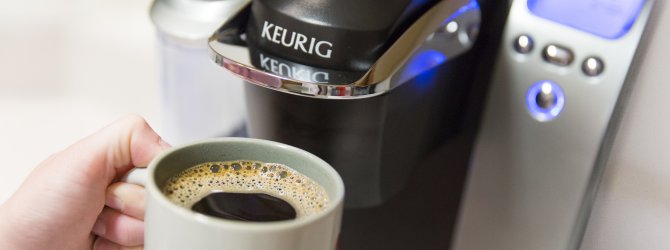 A Keurig coffee maker and a cup of coffee